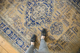 Distressed vintage Oushak carpet with worn navy scalloped medallion and antique ivory field.