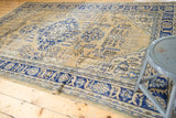 Vintage distressed Oushak carpet corner, showing navy border, ivory field, and faint foundation.