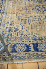 Distressed navy blue and antique ivory Oushak pile with visible knot heads and fringe.