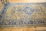 Distressed vintage Oushak rug's navy border and ivory field, highlighting worn texture.