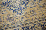 Vintage distressed Oushak rug with ornate navy patterns and soft ivory field texture.