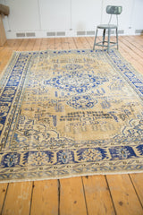 Distressed navy blue border, antique ivory field, and fringe of the Oushak rug.