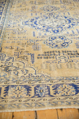 Distressed Oushak rug with ivory field, navy blue faded geometric patterns, and worn pile.
