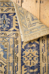 Hand-knotted distressed Oushak rug corner, showing navy blue, ivory patterns and foundation.