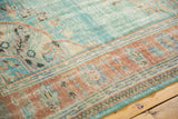 Distressed abrashed aqua green blue field texture meeting a terracotta border with antique ivory scrolling details.