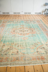 Distressed Oushak carpet edge showing even wear, aqua blue field, and terracotta border.