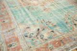 Distressed texture of the Oushak rug, showing muted aqua field and terracotta scrolling motifs.