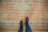 Worn texture of a distressed Oushak carpet, showing faded peach, ivory, and sky blue.