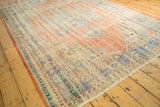 Faded peach, sky blue, and ivory tones on a distressed vintage Oushak rug, highlighting worn pile.