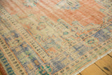 Close-up of vintage distressed Oushak rug's worn texture, faded peach, blue, and ivory patterns.