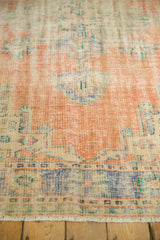 Distressed texture and faded peach, blue, green on a vintage Oushak rug.