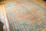 Worn pile texture of the vintage Oushak rug with faded peach, sky blue, and ivory.