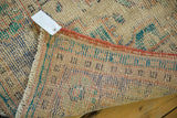 Corner detail of a vintage Distressed Oushak rug, showing worn pile, coral binding, and foundation with markings.
