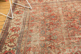 Angled close-up of vintage Persian Mahal rug: brick red Herati motif, ivory, blue, visible wear.