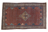 Vintage Persian Serbend rug with a diamond medallion on a red boteh-patterned field and navy blue geometric borders.
