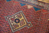 Angled detail of a vintage Serbend rug showing the navy zigzag border and wear with faint foundation.