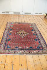 Angled view of a vintage Serbend rug's traditional red and navy geometric design.