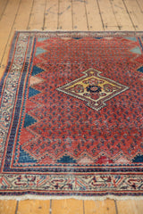 Angled view of the vintage Serbend rug's boteh field, diamond medallion, and zigzag design.