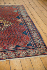 Angled corner view of the vintage Serbend rug's red boteh field and navy zigzag border.