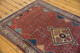 Angled view of a vintage Serbend rug's cherry red boteh field and geometric diamond medallion.