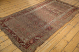 Antique Kurdish rug runner's intricate checkered floral motif and multi-hued border, with visible tatter.