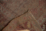 Folded antique Kurdish rug runner displaying woven foundation, tattered edges, and mostly even pile wear.