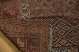 Antique Kurdish runner corner revealing foundation, tattered fringe, and intricate checkered floral motif.