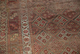 Antique Kurdish rug detail: intricate checkered floral motif, geometric border, wine red hues.