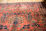 Dusty brick red field with navy and beige blooming florals on a vintage Sarouk rug.
