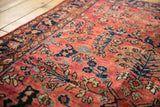 Vintage American Sarouk rug, low pile dusty red field with navy and ivory floral motifs.