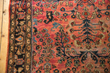 Vintage American Sarouk rug detail: low pile dusty red floral field with navy border.