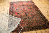 Curvilinear floral motifs on a vintage Sarouk rug's dusty brick red and navy field.