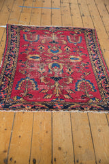 Vintage Lilihan rug corner: cherry red field, navy border, floral pattern, and tattered selvage.