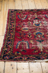 Vintage Lilihan rug corner with cherry red field, navy blue floral border, and visible low pile.