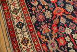 Detail of vintage Malayer rug border with ivory medallions and red banding, next to the navy field.