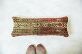 Handmade antique rug fragment pillow with rustic geometric patterns and faded tones.