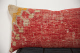 Antique Turkish rug fragment pillow with distressed red, cream, and faded yellow patterns.
