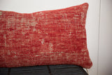 Close-up of distressed red antique Turkish rug fragment pillow with faded patterns.