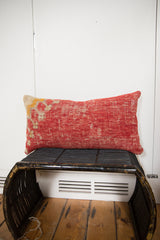 Antique Turkish rug fragment pillow with distressed red, beige, and yellow tones.