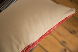 Smooth neutral beige remnant fabric backing and woven red edge of the Turkish pillow.