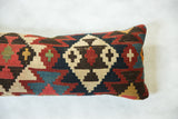 Detailed geometric pattern on antique Kilim pillow featuring red, navy, and cream stepped diamonds.
