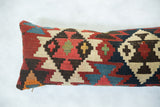 Close-up of hand-woven geometric pattern on antique kilim pillow in red, blue, and cream.