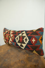 Vibrant geometric pattern of the antique kilim pillow in red, navy, and cream.