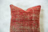 Textured antique Turkish rug fragment pillow with mottled red and natural beige tones.