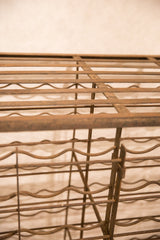 Rustic brown texture and wavy bottle holders on antique French iron wine rack.