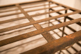 Antique French iron wine rack grid with textured reddish-brown patina and signs of age.