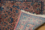 Corner of vintage Kerman runner showing hand-knotted foundation, original selvage, and dusty red floral pile.