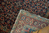 Folded vintage Hamadan rug revealing tight foundation weave and colorful Herati motif.
