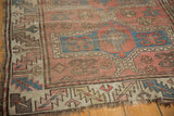 Geometric border of an antique Caucasian rug with brick red and cobalt blue, showing low pile and worn fringe.
