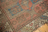 Caucasian rug's tattered end showing wear, brick red, and cobalt blue geometric patterns.